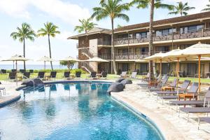 a resort with a pool and chairs and umbrellas at Koa Kea Resort on Poipu Beach in Koloa