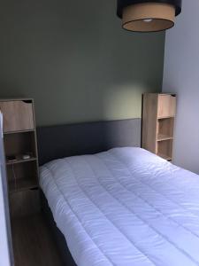 um quarto com uma cama branca e 2 prateleiras em Centre ville de Luchon em Luchon