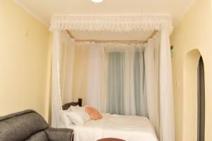 a bedroom with a white canopy bed with a window at Woodgreek Studio Fully Furnished Apartment in Kisii