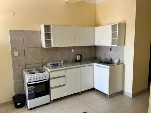 a kitchen with white cabinets and a stove top oven at Dtos las brisas in La Banda