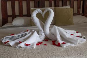 サンホセにあるEco Stay Hostelの赤いハートのベッドに置いた白鳥のタオル2枚