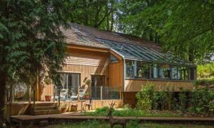 Eine Frau steht vor einem kleinen Haus. in der Unterkunft 5 Star Luxury Woodland Retreat Sleeps 12 Hot tub Sauna in Clapton in Gordano