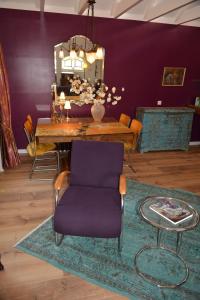 uma sala de jantar com uma mesa e uma cadeira roxa em Wonderland em Pieterburen