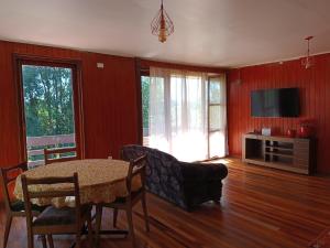 sala de estar con mesa y TV en HOSTEL Casa de campo Niña bosque, en Valdivia