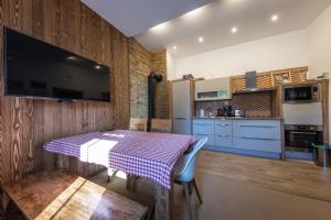 a kitchen with a table and a tv on a wall at Vila Mudroň in Vysoke Tatry - Dolny Smokovec