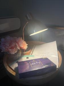 a table with a lamp and a book and a flower at Honeysuckle Cottage & Whinfell Studio in Penrith