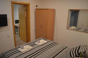 a bedroom with a bed with two pillows and a mirror at Apartman N&A in Novi Sad