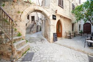an alley with an archway in a stone building at Palace Derossi in Trogir