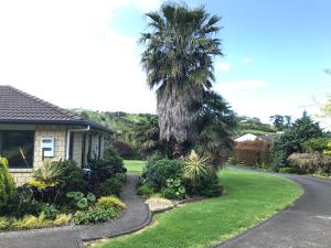 a house with palm trees next to a driveway at Silverdale Garden Studio in Orewa