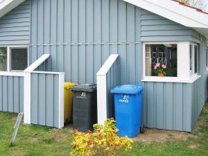 una casa azul con dos cubos de basura y una ventana en 6 person holiday home in Otterndorf, en Otterndorf