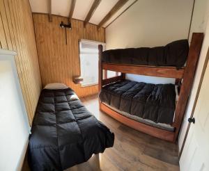 アラウコにあるCabaña Pilpilen - Curaquilla Lodge "Entre humedales y el Mar"の二段ベッド2台と寝袋が備わる客室です。