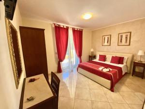 1 dormitorio con 1 cama con cortinas rojas y mesa en B&B Mareagrò, en Santa Teresa di Riva