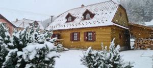 Casa de madera con techo cubierto de nieve en Holidayhouse Chalupa Alžbetka, en Važec