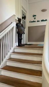 a staircase with a statue of a person holding an umbrella at A l'Ombre des tilleuls in Husseren-Wesserling