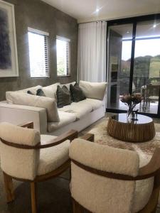a living room with a white couch and two chairs at 1 The Eighteenth, Prince’s Grant Golf Estate in Blythedale