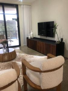 a living room with a tv and two chairs and a table at 1 The Eighteenth, Prince’s Grant Golf Estate in Blythedale