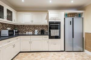 een keuken met witte kasten en een koelkast bij Abercorn Lodge Semi-Detached House in Edinburgh