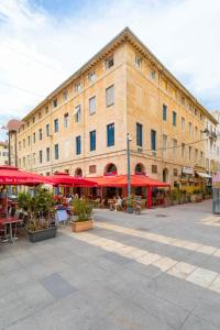 um grande edifício com mesas e guarda-chuvas vermelhos em Sunny Stylish Spacious Loft in Old-Port em Marselha