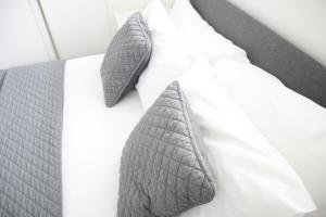 - un lit avec une cravate gris sur un oreiller blanc dans l'établissement Twelve Thirty Serviced Apartments - Balham, à Londres