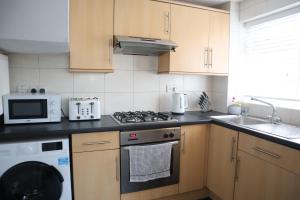 a kitchen with a stove and a microwave at Twelve Thirty Serviced Apartments - Balham in London