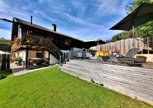 a house with a patio with chairs and an umbrella at Das Hof Chalet in Ehrwald