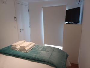 a bedroom with a bed with three towels on it at Lugar de Santana in Sesimbra