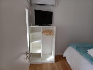 a white cabinet with a tv and a bed at Lugar de Santana in Sesimbra