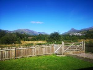 una valla de madera con una puerta con montañas en el fondo en Cosy double room in peaceful location, Ballachulish nr Glencoe Highlands en Ballachulish