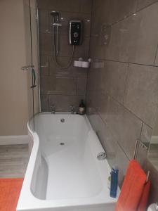 a bathroom with a bath tub with a shower at Cosy double room in peaceful location, Ballachulish nr Glencoe Highlands in Ballachulish