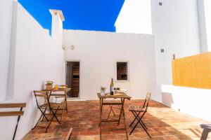 un patio con tavoli e sedie in legno e una parete bianca. di Female Hostel a Faro