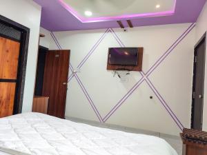 a room with a bed and a tv on a wall at Hotel Sardar Rooms in Garudeshwar