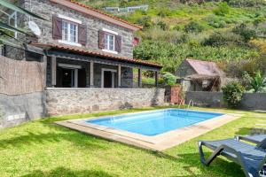 a swimming pool in a yard next to a house at Casa do Pombal, a Home in Madeira in Arco da Calheta