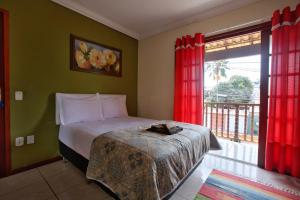 a bedroom with a bed and a large window at Suites Palmeiras Cabo Frio in Cabo Frio