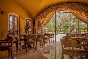 een restaurant met tafels en stoelen en een groot raam bij HC HACIENDA CATRINA HOTEL BOUTIQUE in Silao