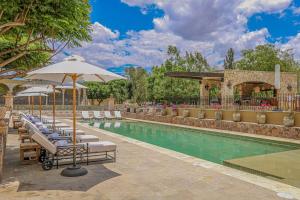 a swimming pool with lounge chairs and an umbrella at HC HACIENDA CATRINA HOTEL BOUTIQUE in Silao