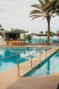 a swimming pool with palm trees and umbrellas at Tibisay Hotel Boutique Margarita in Porlamar