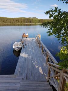 a wooden dock with a boat on the water at Hugsnäset Semesterstugor och Fiske in Gällö