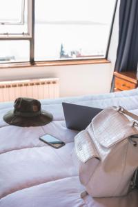a hat and a purse on a bed with a laptop at Tangoinn Hostel Downtown in San Carlos de Bariloche