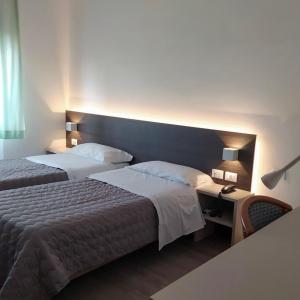 Habitación de hotel con 2 camas y mesa con lámpara en Hotel Friuli en Cervignano del Friuli
