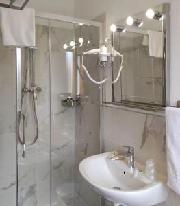 y baño con lavabo y ducha con espejo. en Hotel Friuli en Cervignano del Friuli
