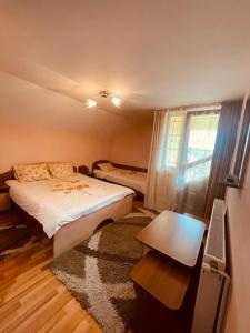 - une chambre avec un lit, un bureau et une fenêtre dans l'établissement Pensiunea Valea Ursului, à Cîmpulung