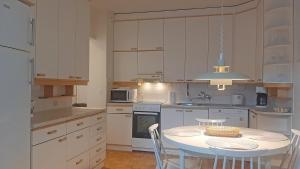 una cocina con mesa y sillas y una cocina con armarios blancos. en Apartment Puijo & autotalli, en Kuopio