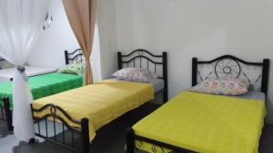 two beds in a room with yellow and green sheets at Helena Hostel in Cali