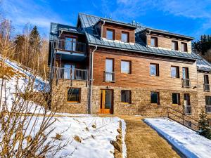 a large brick house with snow on the ground at Apartman Bratrouchov in Jablonec nad Jizerou