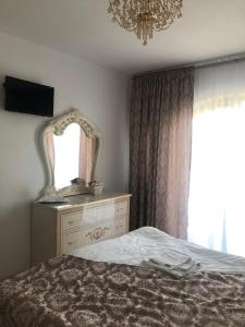 ein Schlafzimmer mit einem Bett, einem Spiegel und einer Kommode in der Unterkunft FLORENA HOUSE in Pecineaga