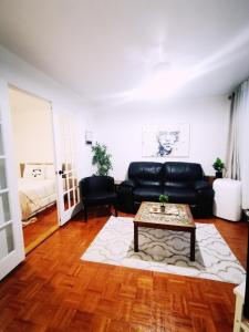 ein Wohnzimmer mit einem schwarzen Ledersofa und einem Couchtisch in der Unterkunft Plush 2 bedroom unit 5min Downtown Off Wellington in Montreal