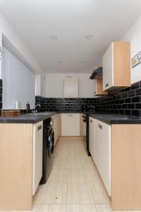 a kitchen with white cabinets and black tiles at Beech House Leeds in Leeds