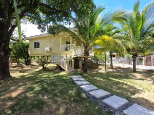 een geel huis met een veranda en palmbomen bij Single-Family Home With Gated Tropical Yard in Roatan