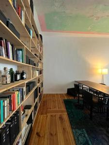 a room with a library with a table and book shelves at Schönes Loft mit Kamin in Mitte Gesundbrunnen in Berlin