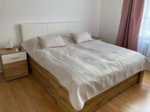 Apartmán Monika في Kraslice: غرفة نوم بسرير مع اطار خشبي وموقف ليلي